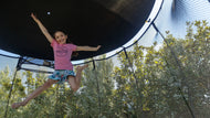 Load image into Gallery viewer, young girl jumping high on a trampoline with sun shade